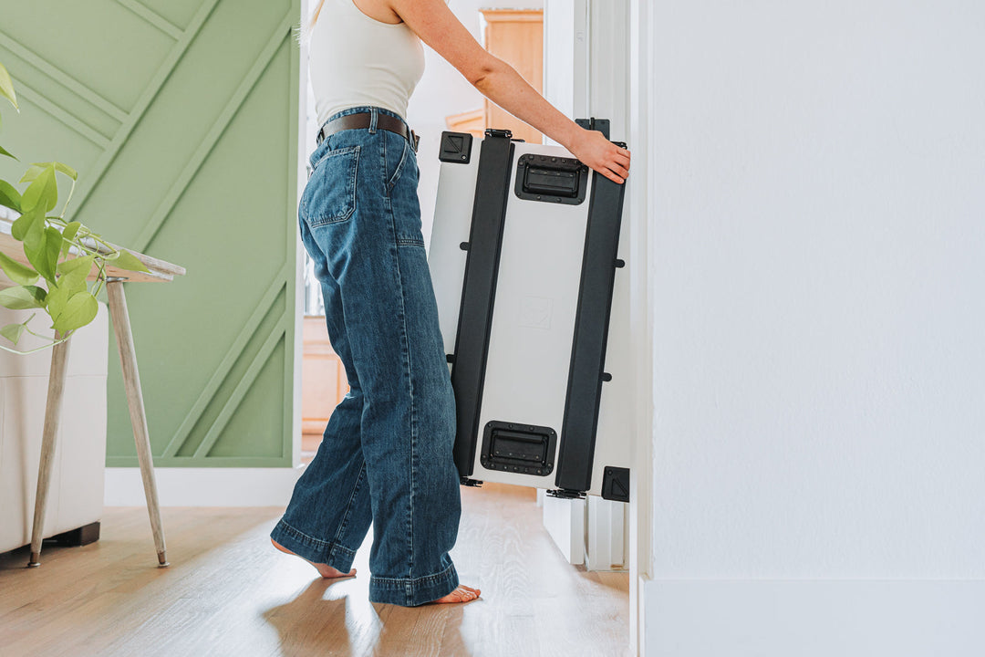 a woman putting her white collapsible dog crate in the closet demonstrating the space saving magic
